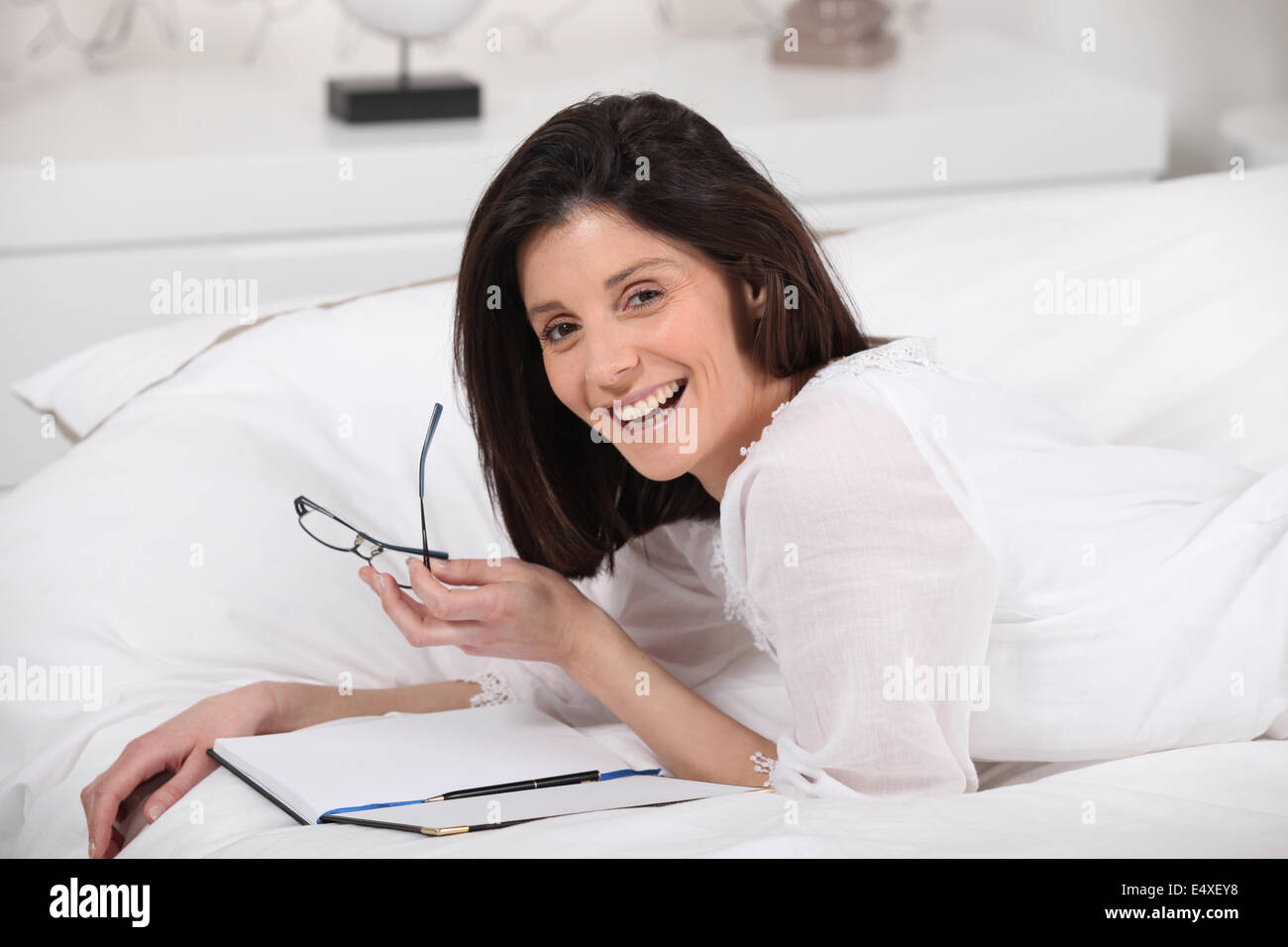 glückliche Frau lesen im Bett Stockfoto