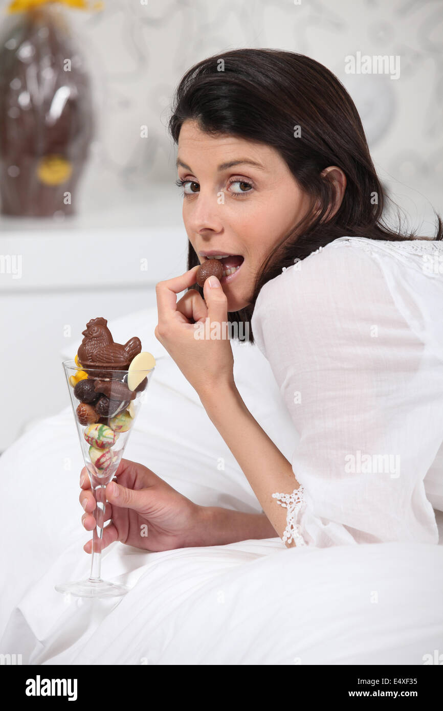 Frau im Bett Schokolade essen Stockfoto