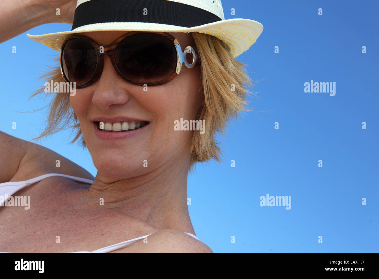 Frau mit Sonnenbrille und Strohhut Stockfoto