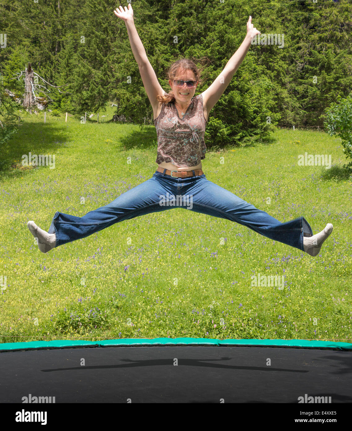 Eine junge Frau auf einem Trampolin in einer Berglandschaft mit Freude hüpfen Stockfoto
