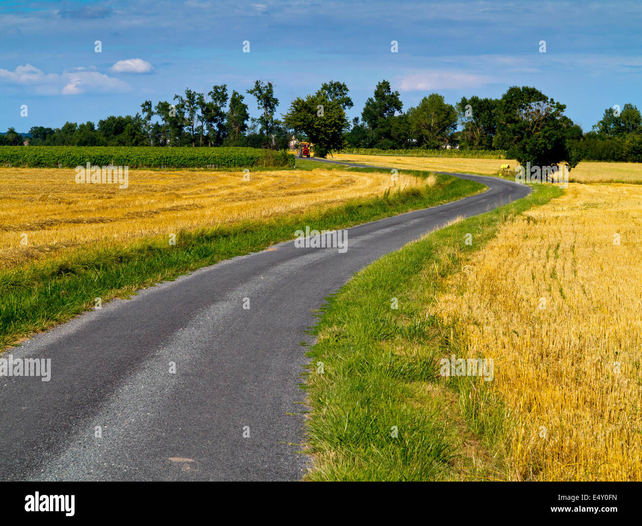 Kurvenreiche leeren Landstraße in der Nähe des Dorfes Perignac in Süd-West Frankreich mit Felder entweder Seite und ein Traktor in der Ferne Stockfoto