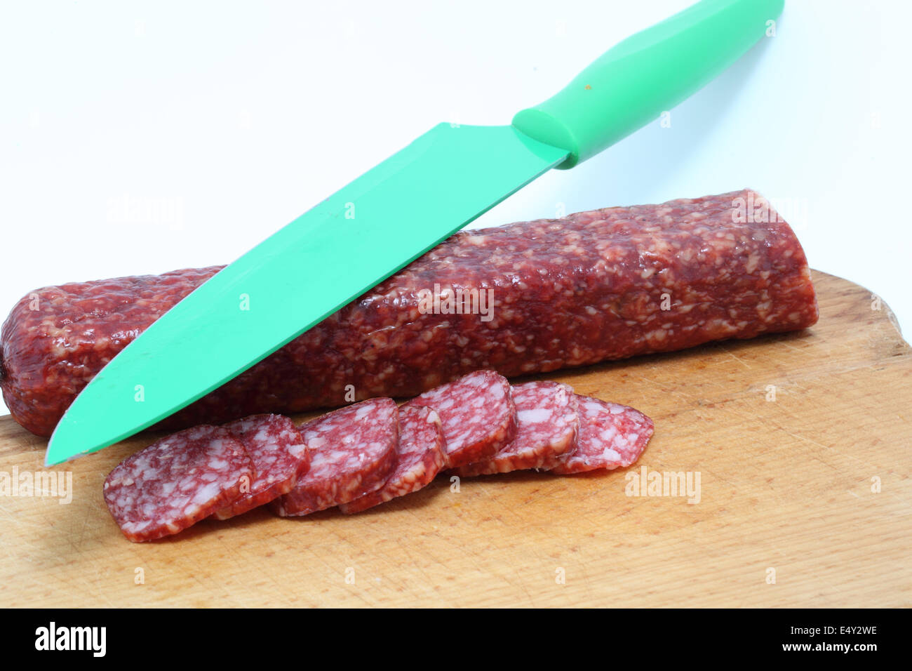 in Scheiben geschnittene Wurst und Messer isoliert auf weiss Stockfoto