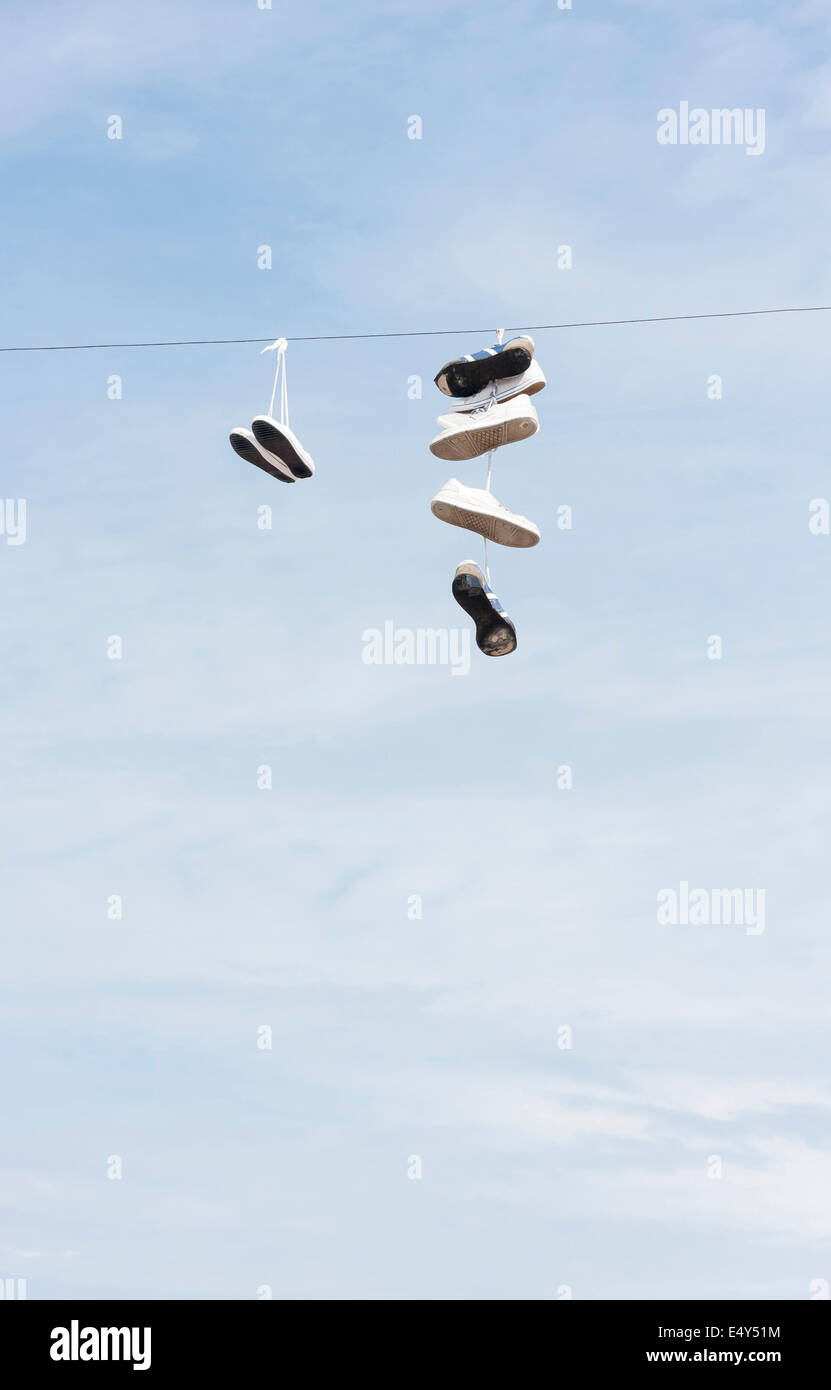 Viele alte abgenutzte Stiefel oder Schuhe, die an ein elektrisches Kabel hängen Stockfoto