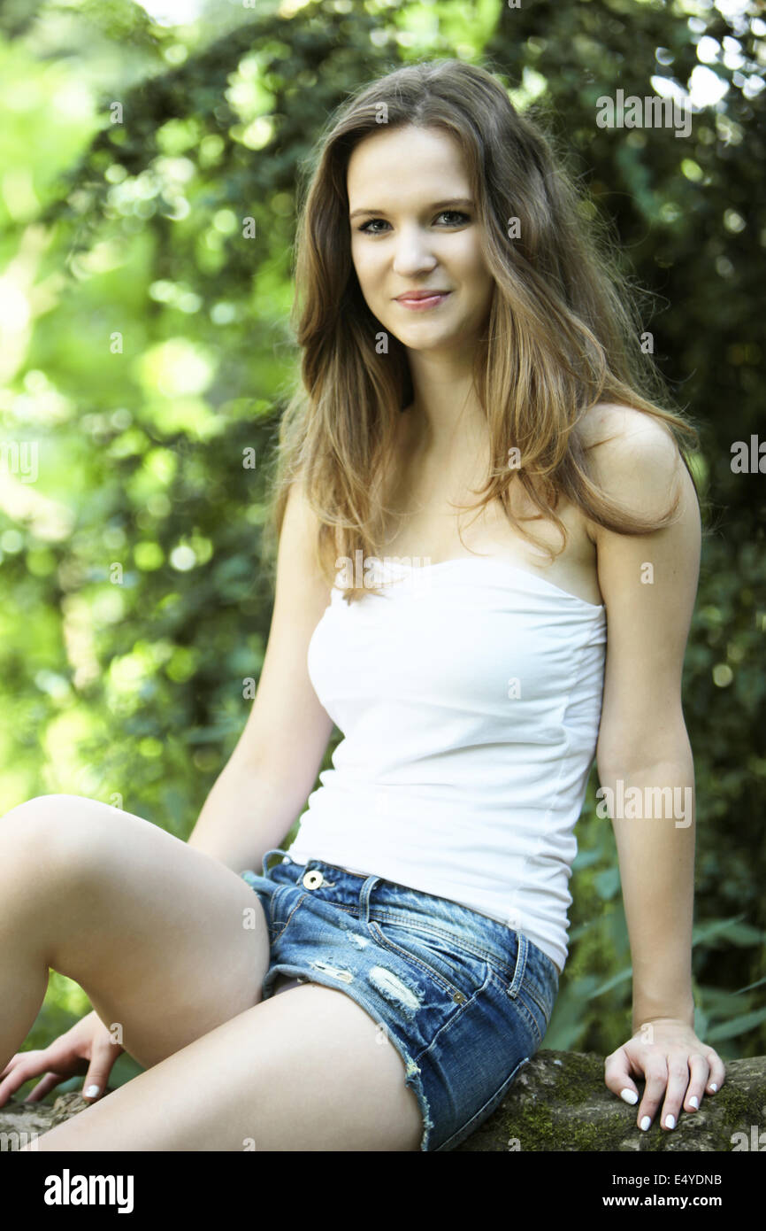 Schöne junge Frau, die im Garten zu sitzen Stockfoto