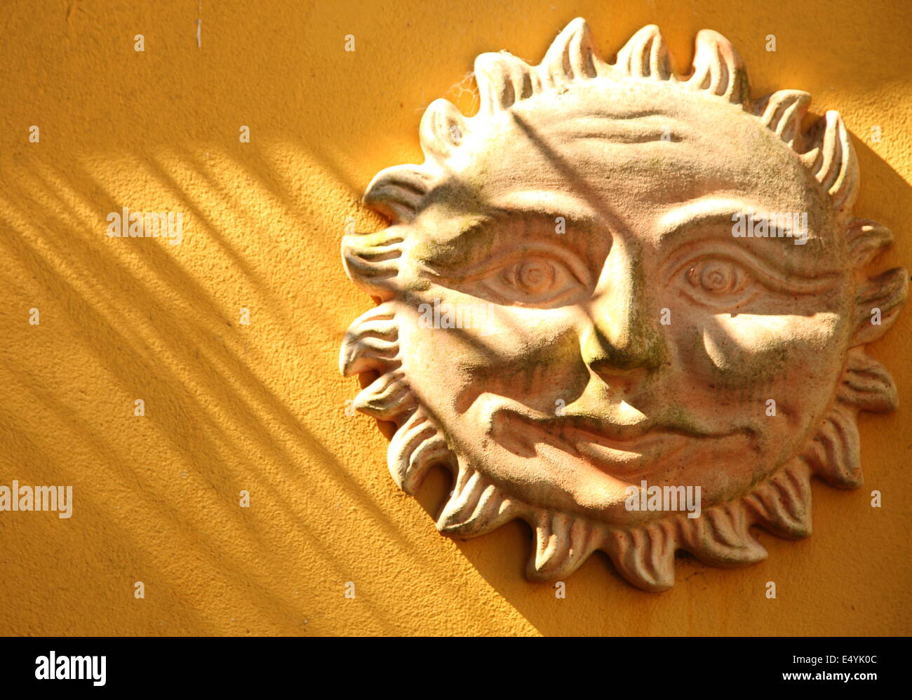 Terrakotta, die lächelnde Sonne an einer Wand Stockfoto