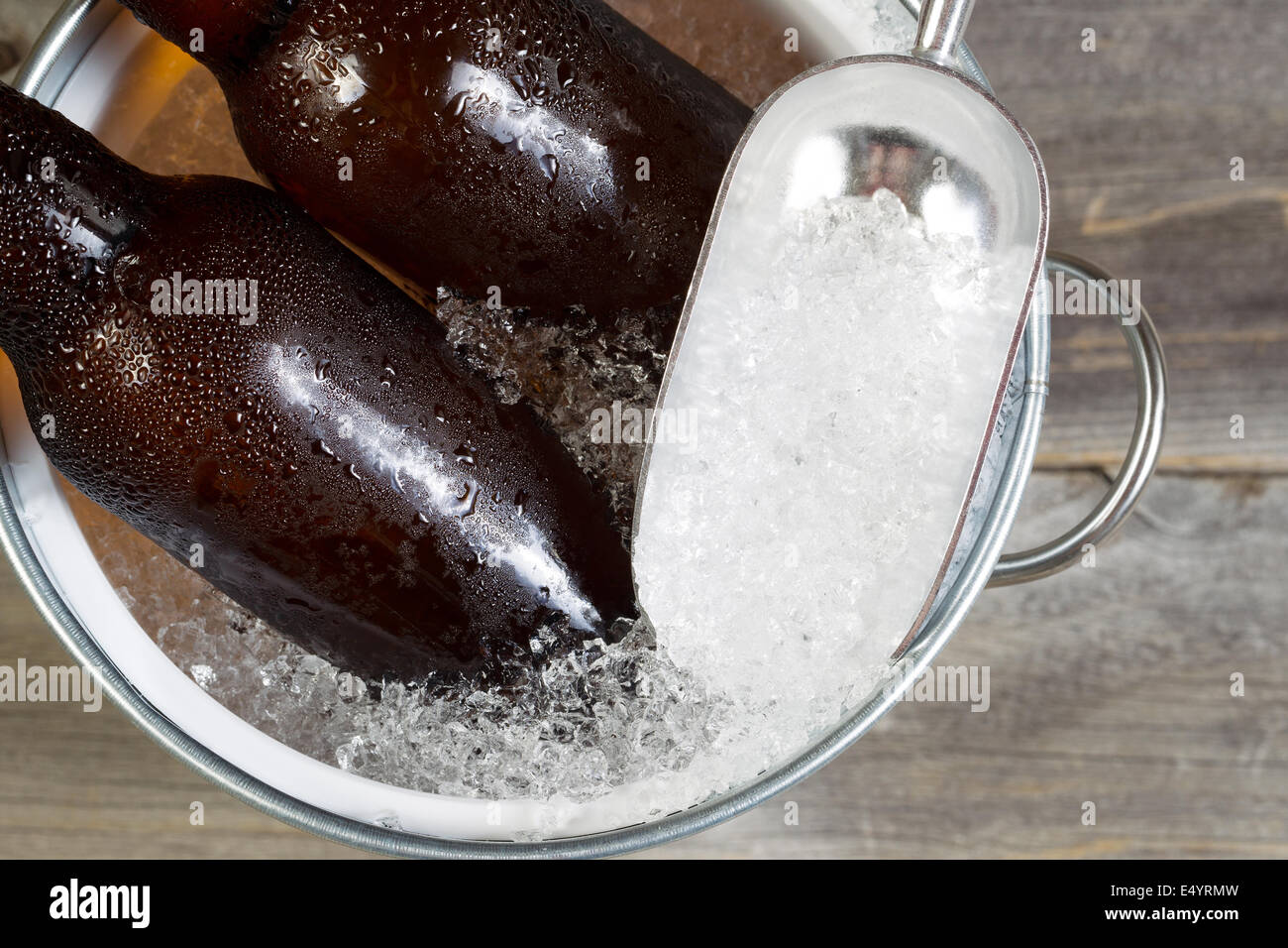 Closeup Draufsicht des teilweise frisch abgefülltes Bier sitzen in Blecheimer gefüllt mit zerstoßenem Eis, Scooper und rustikale Holz in Stockfoto