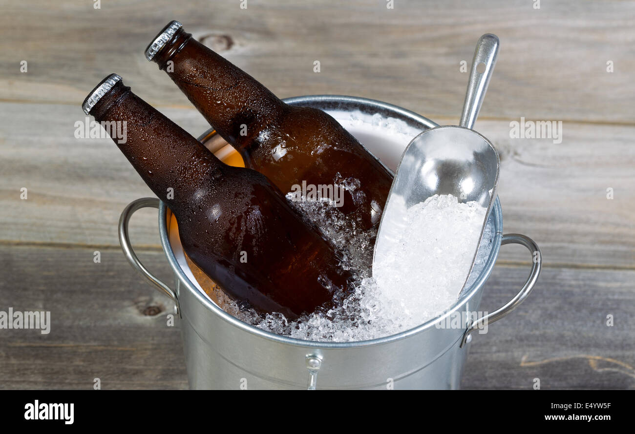 Closeup Draufsicht des frisch abgefülltes Bier sitzen in Blecheimer gefüllt mit zerkleinerten Eistee und rustikale Holz im Hintergrund Stockfoto