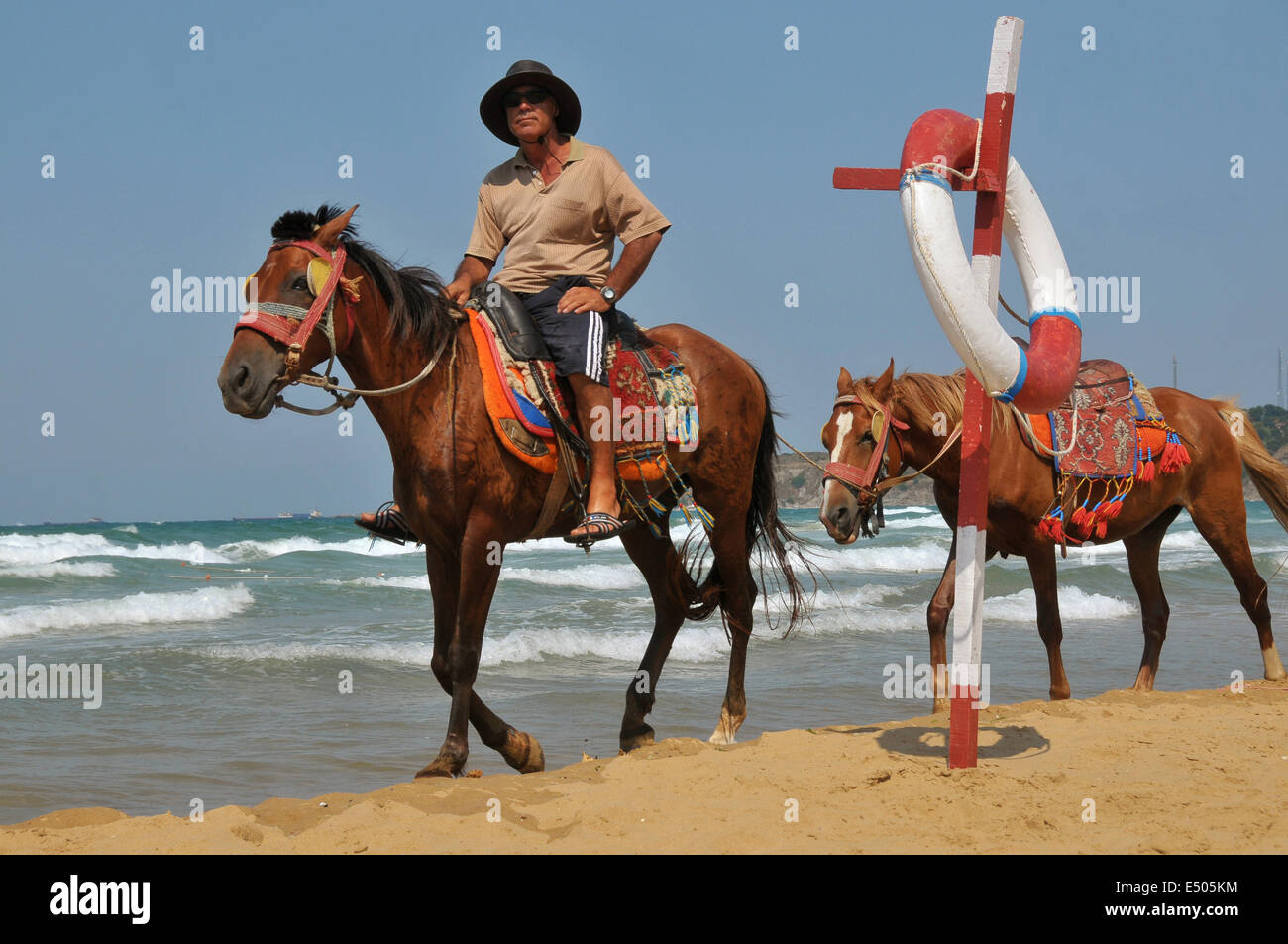 Ein Mann reitet seine Pferde Vermietung entlang des Strandes in Kilyos (auch genannt Kumköy), ein kleiner Badeort am Schwarzen Meer in der Nähe von Istanbu Stockfoto