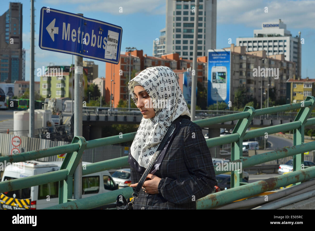 Eine türkische Frau trägt ein Kopftuch und Mantel geht auf eine Fußgängerbrücke in der Geschäft Bezirk von Levent. Stockfoto