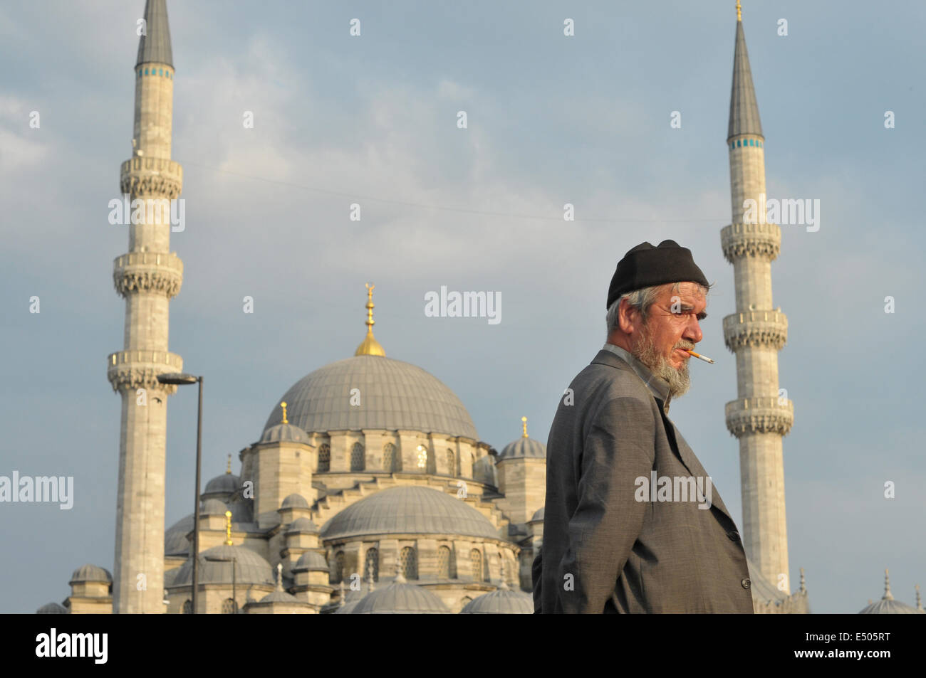 Ein älterer Türke Spaziergänge entlang der Uferpromenade in Eminönü mit Yeni Camii (neue Moschee) im Hintergrund. Stockfoto