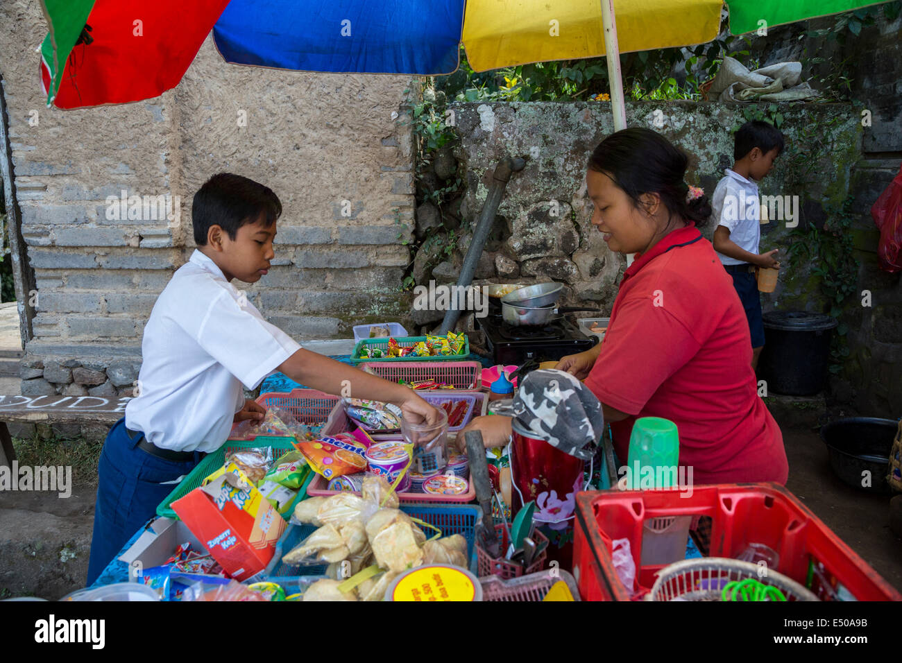 Bali, Indonesien.   Schuljunge Kauf Erfrischungen bei einer Erfrischung stehen außerhalb seiner Schule.  Tenganan Dorf. Stockfoto