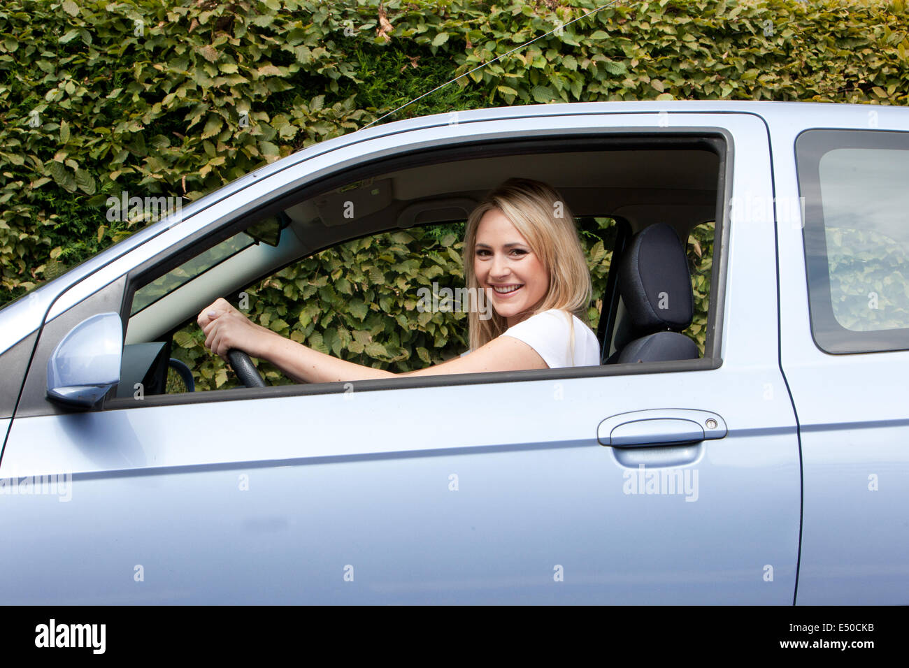 Lächelnde Frau, die ihr Auto zu fahren Stockfoto