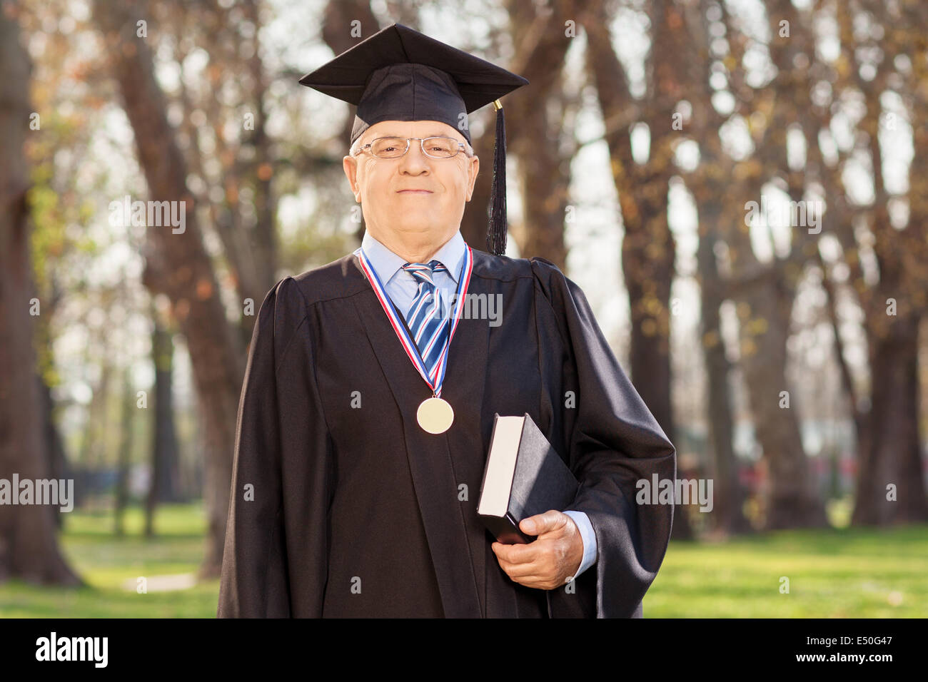 Dekan der Hochschule posiert mit einem Buch in einem Hof Stockfoto