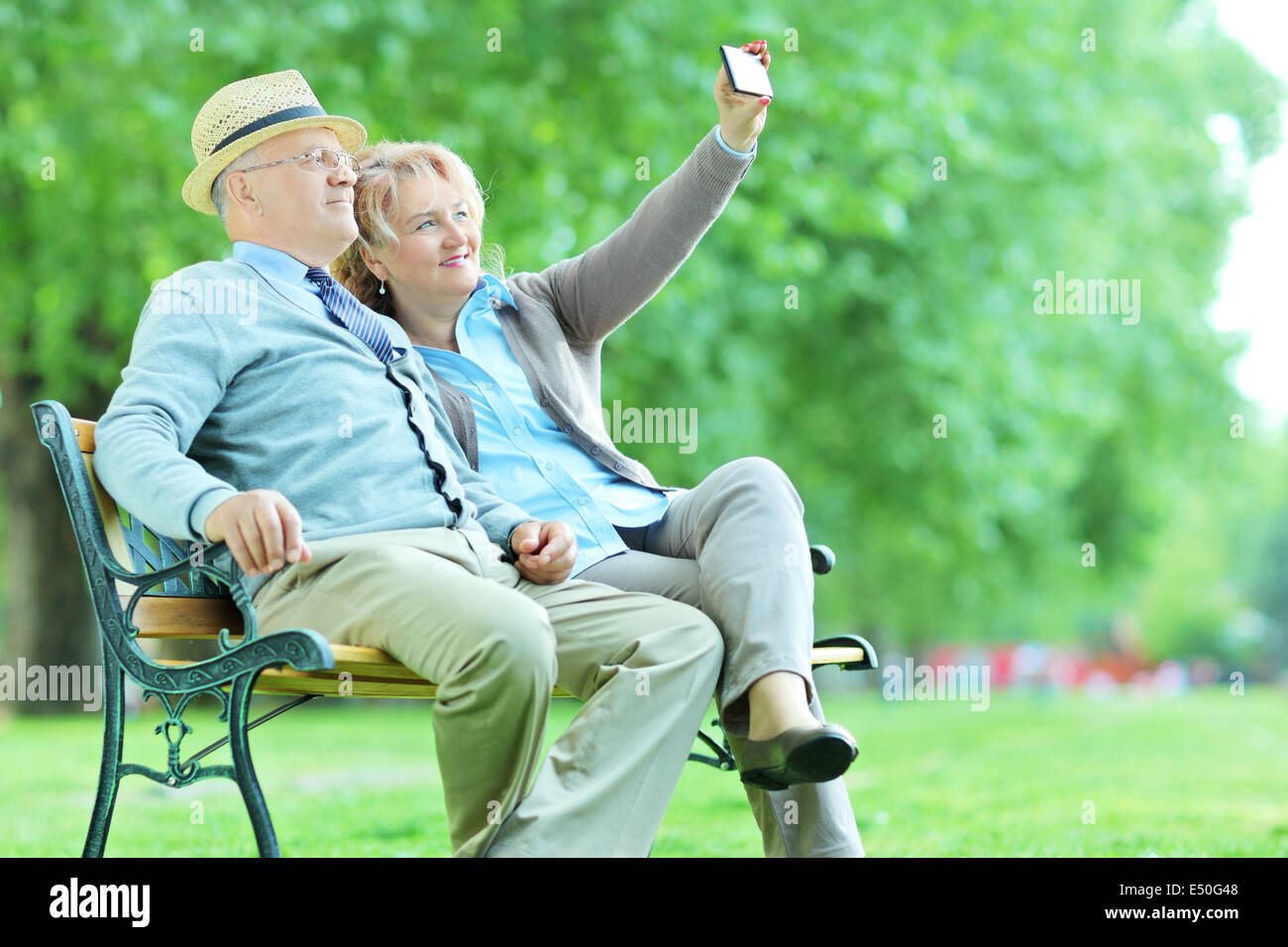 Älteres Ehepaar nehmen ein Selbstporträt im Park sitzend auf Bank Stockfoto