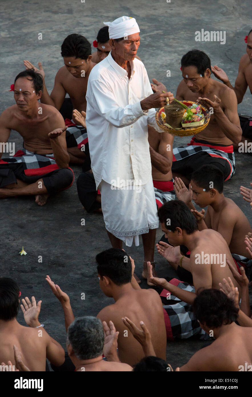 Bali, Indonesien.  Hindu Priester besprüht Wasser auf Tänzer in den Kecak-Tanz, Arena neben Uluwatu Tempel. Stockfoto