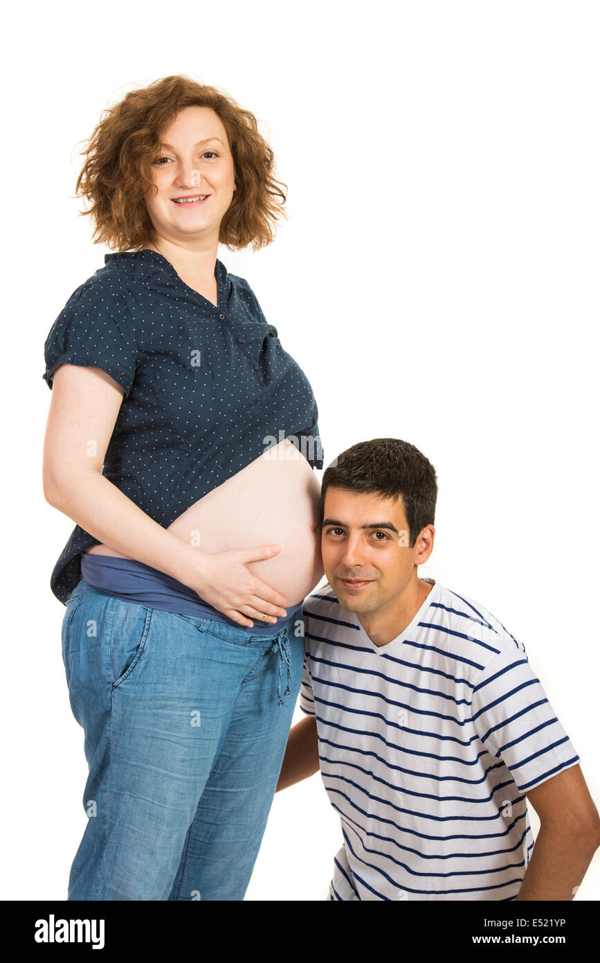 Zukünftige Vater anhören seiner Frau schwangeren Bauch isoliert auf weißem Hintergrund Stockfoto