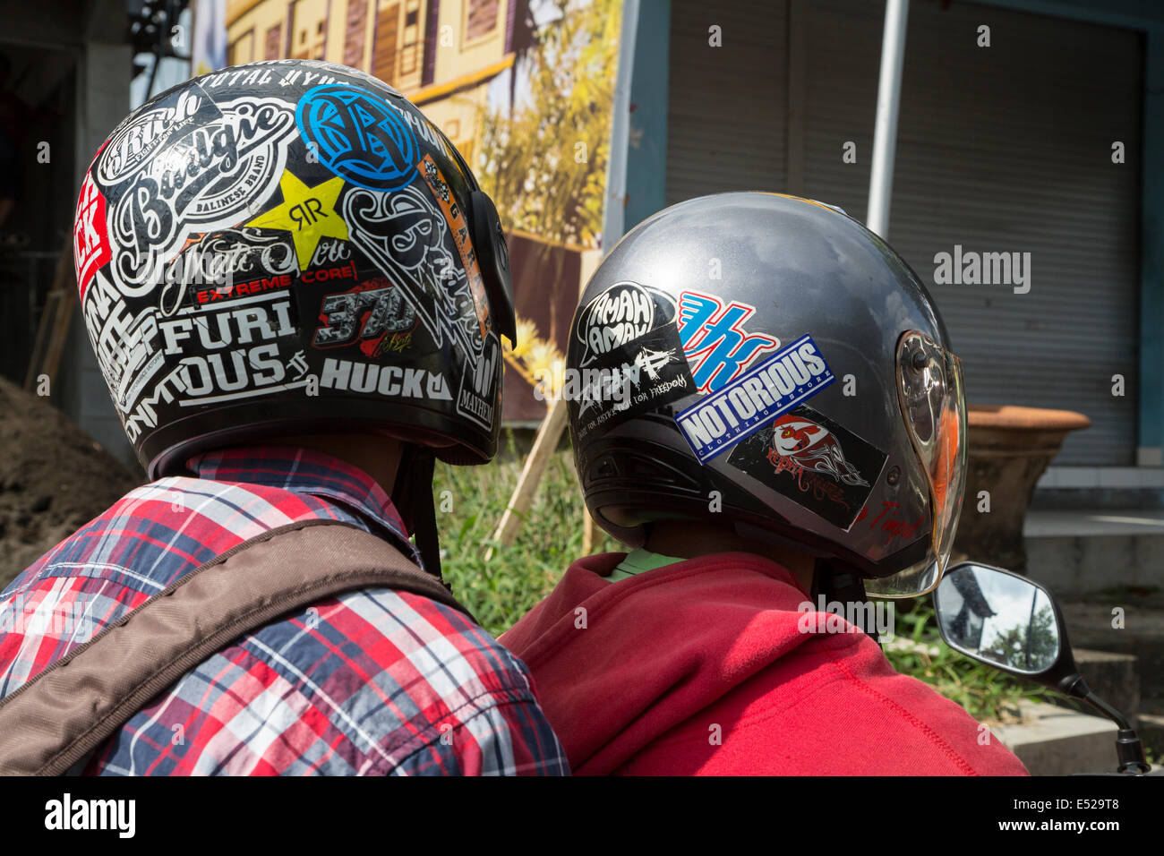 Bali, Indonesien.  Zwei junge Männer auf einem Motorrad mit Helmen. Stockfoto