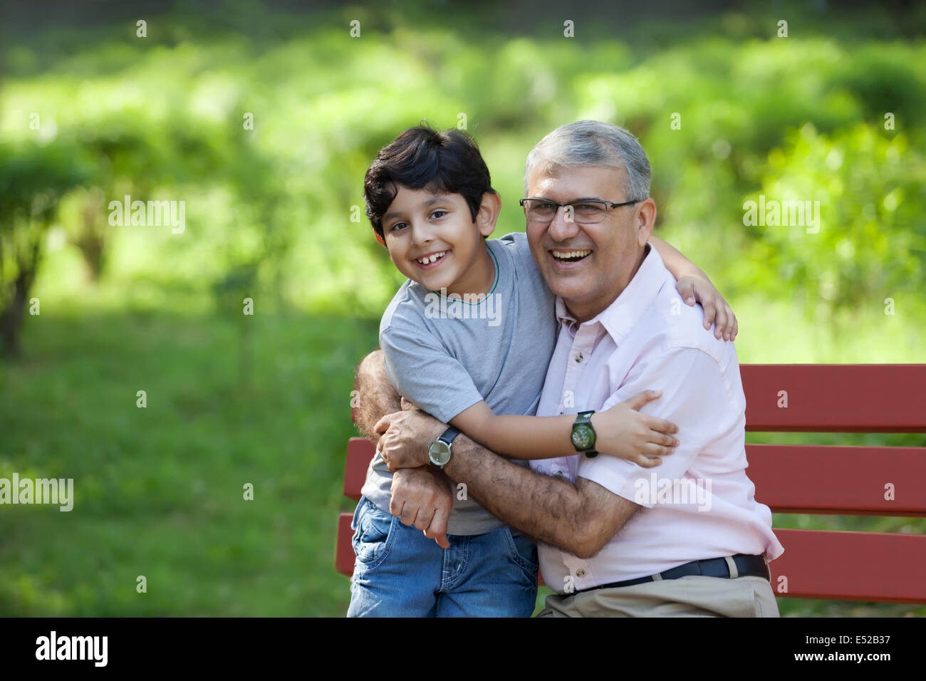 Porträt von Großvater und Enkel, die in einem Park umarmt Stockfoto