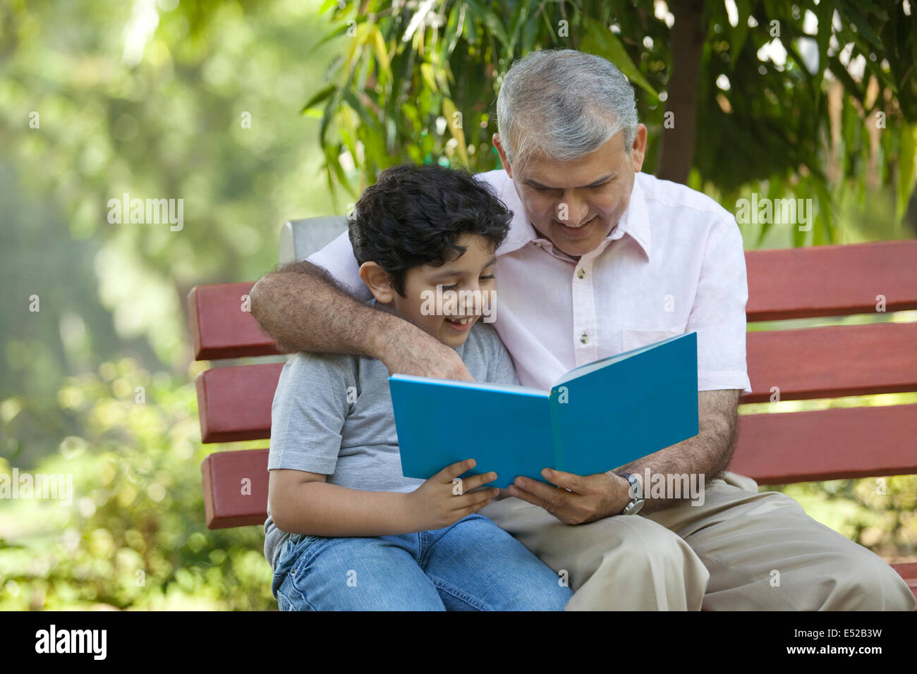 Großvater und Enkel, die ein Buch in einem park Stockfoto