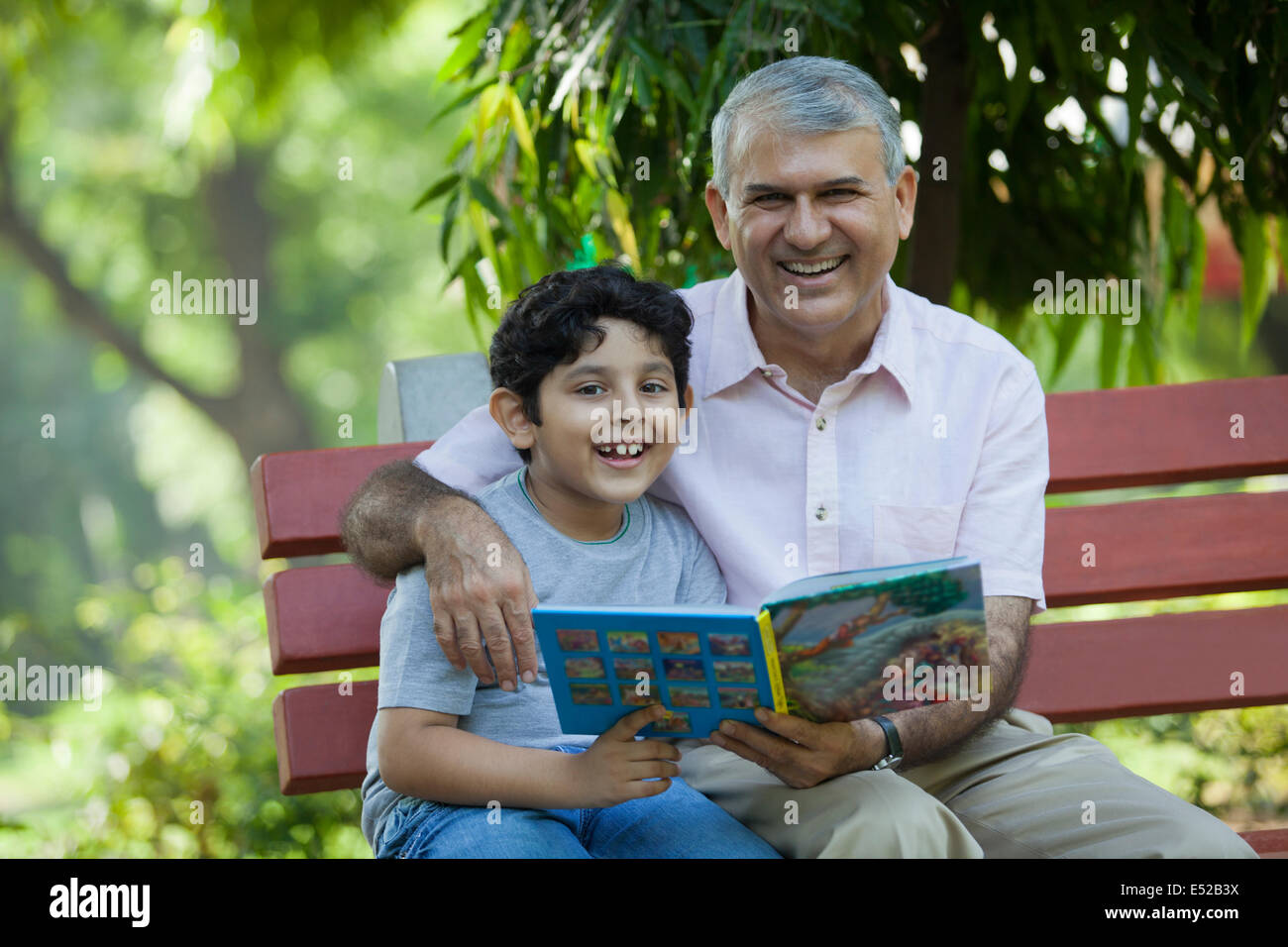 Porträt von Großvater und Enkel mit einem Buch in einem park Stockfoto