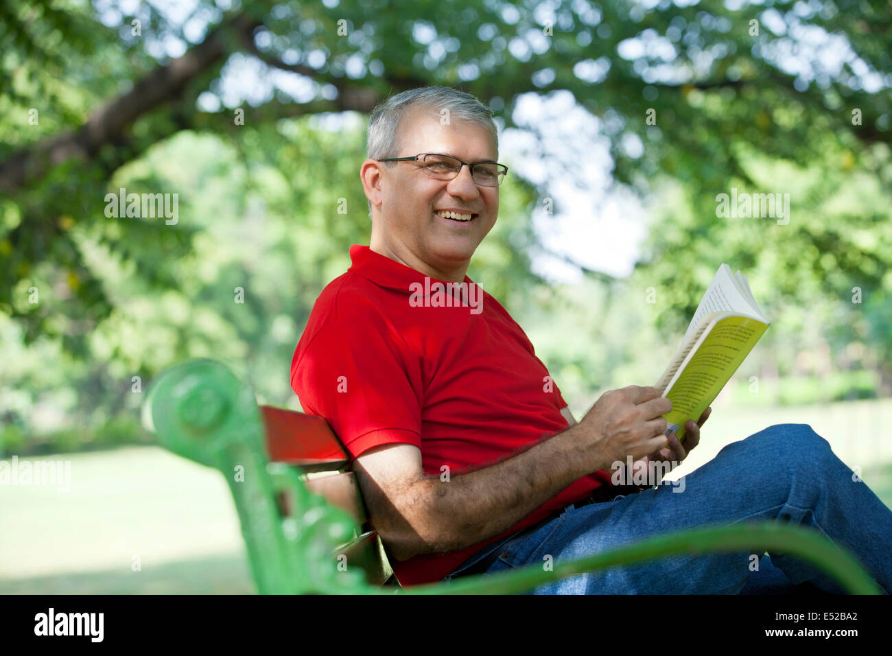 Porträt eines älteren Mannes Lesen eines Buches in einem park Stockfoto
