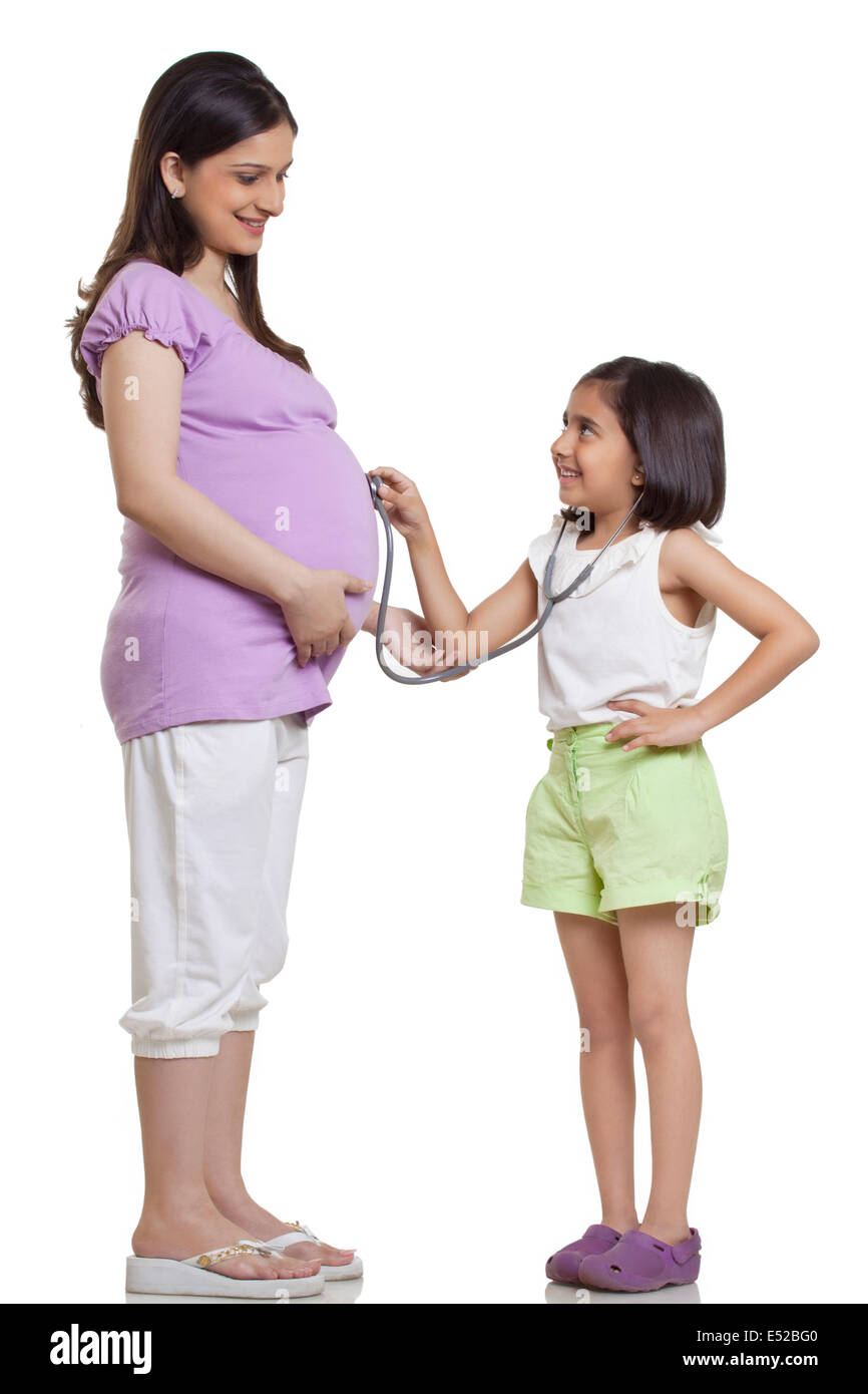 Tochter Holding Stethoskop, schwangere Mutter Bauch Stockfoto