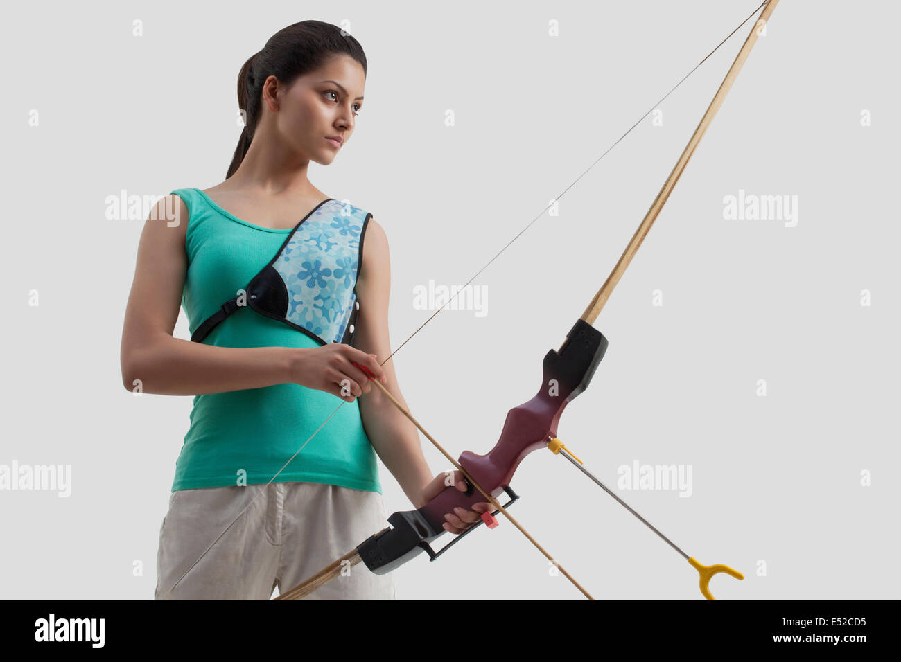 Weibliche Bogenschützen mit Pfeil und Bogen auf grauem Hintergrund isoliert Stockfoto