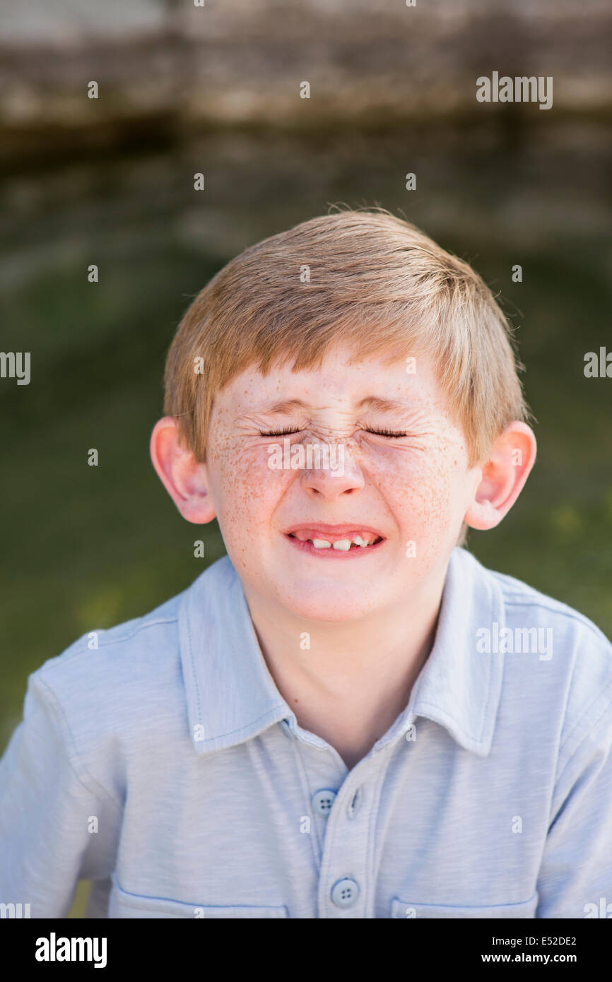 Ein Junge in ein blaues Hemd, seine Nase zu vermasseln. Stockfoto