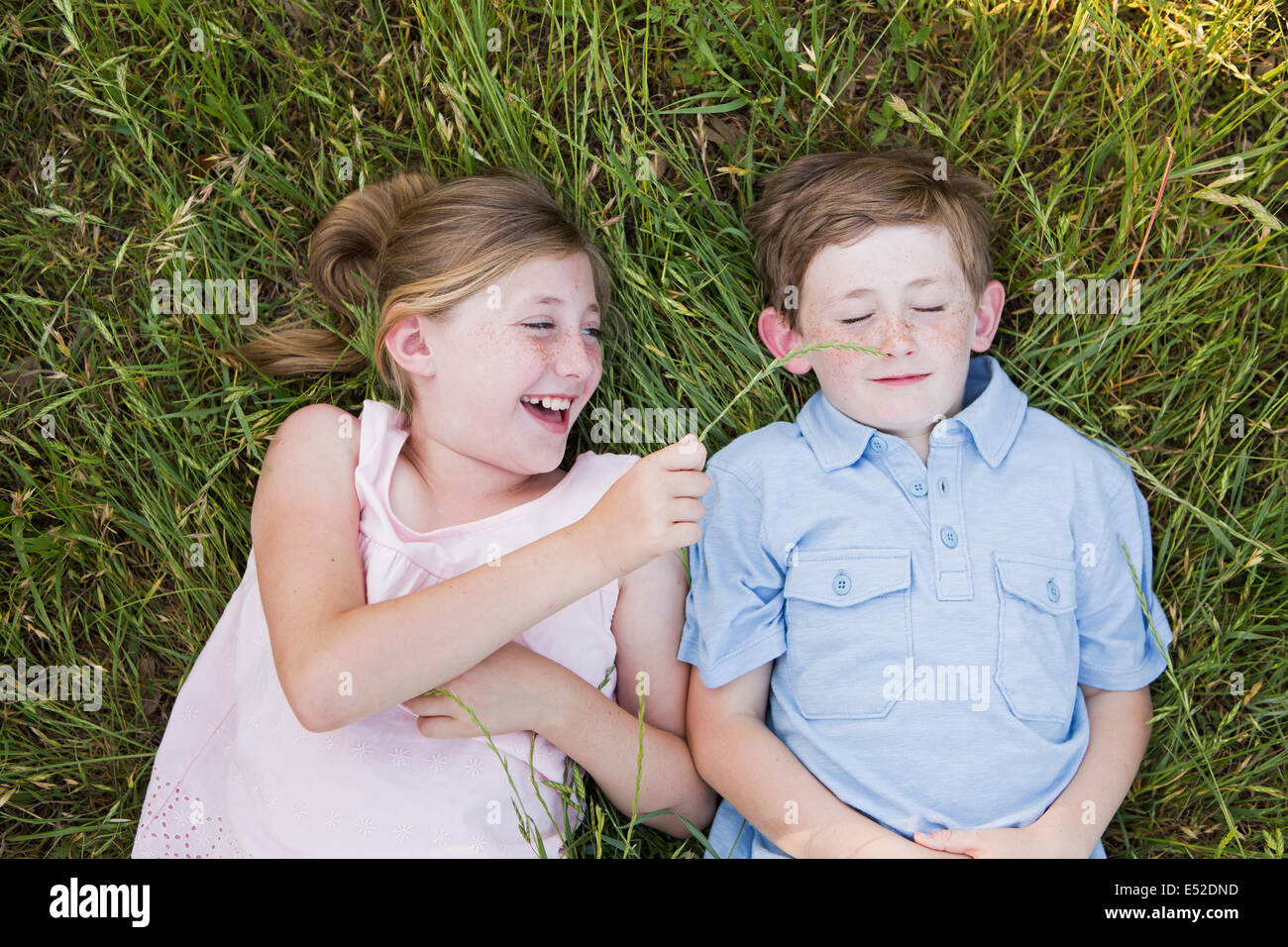 Zwei Kinder, Bruder und Schwester liegen nebeneinander auf dem Rasen Stockfoto