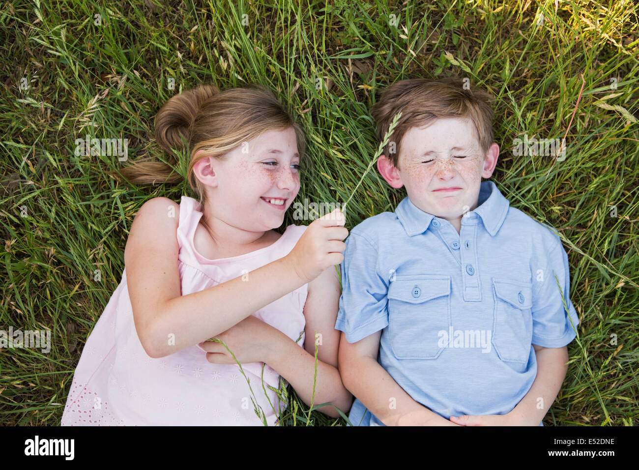 Zwei Kinder, Bruder und Schwester liegen nebeneinander auf dem Rasen Stockfoto