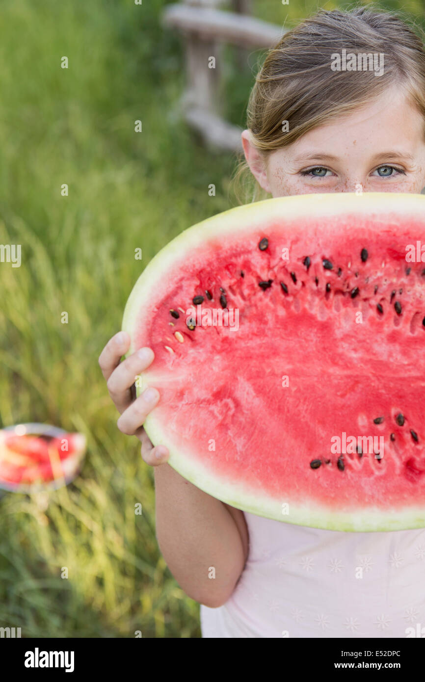 Ein Kind hält eine halbe Melone ein frisches Wasser. Stockfoto