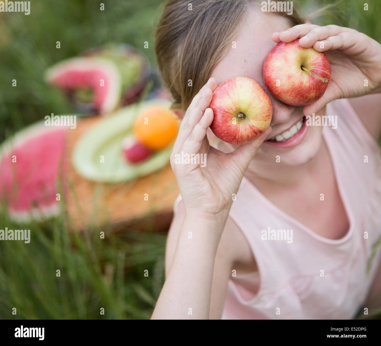 Ein Mädchen hält zwei Äpfel vor ihren Augen Stockfoto