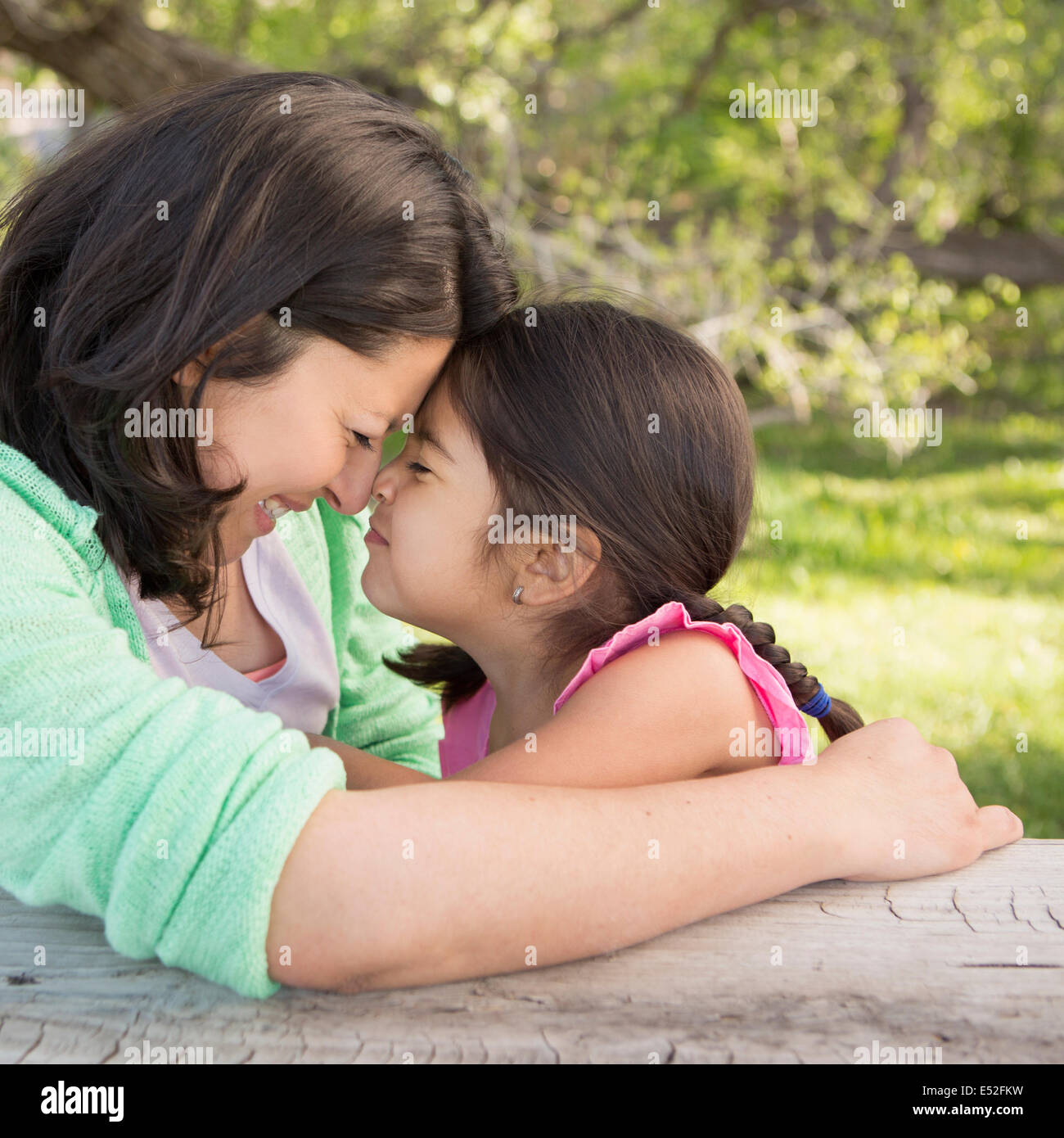 Eine Mutter im Park mit ihrer Tochter, lachen und küssen einander. Stockfoto