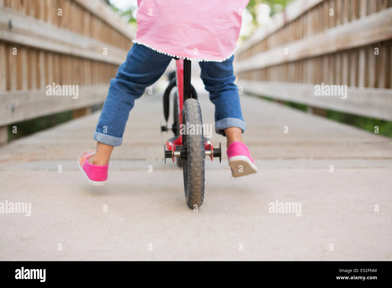 Ein Kind reitet auf einem Fahrrad auf einem Holzsteg. Stockfoto
