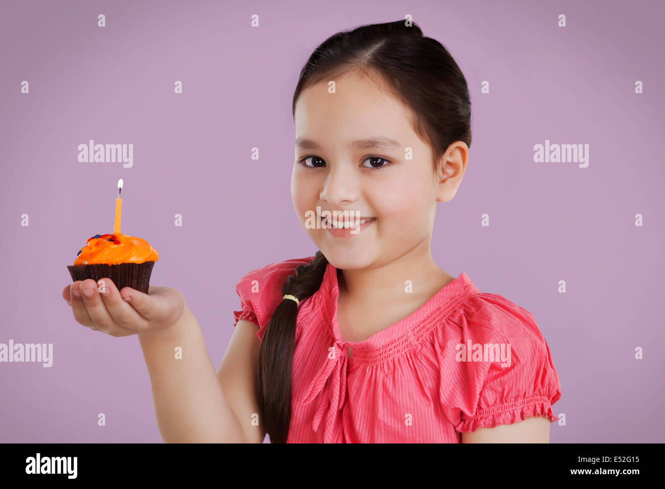 Porträt eines Mädchens hält einen kleinen Kuchen mit einer Kerze Stockfoto
