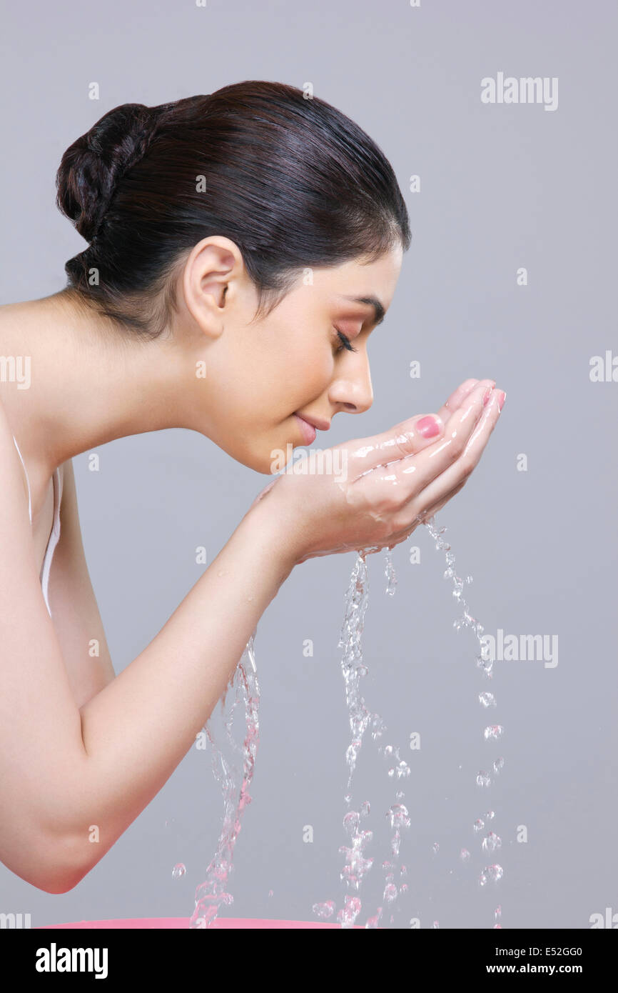 Seite vie junge Frau waschen Gesicht vor grauem Hintergrund Stockfoto