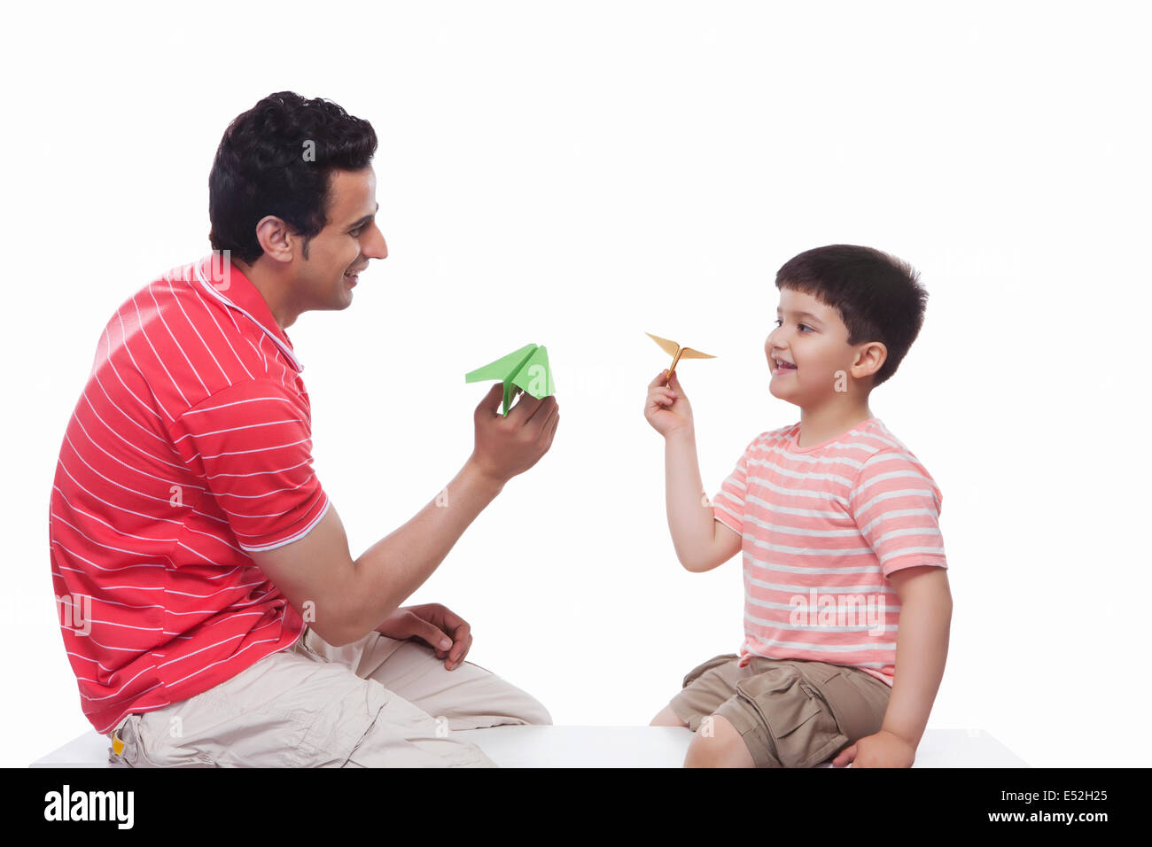 Glücklicher Vater und Sohn spielen mit Papierflugzeug vor weißem Hintergrund Stockfoto