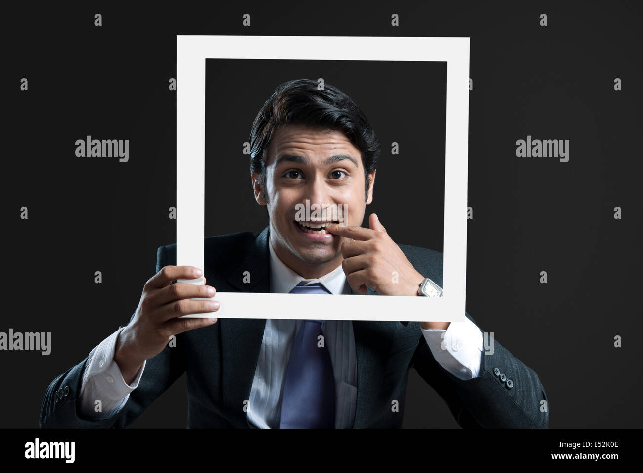 Porträt des jungen Geschäftsmann mit Finger im Mund Halterahmen auf schwarzem Hintergrund Stockfoto