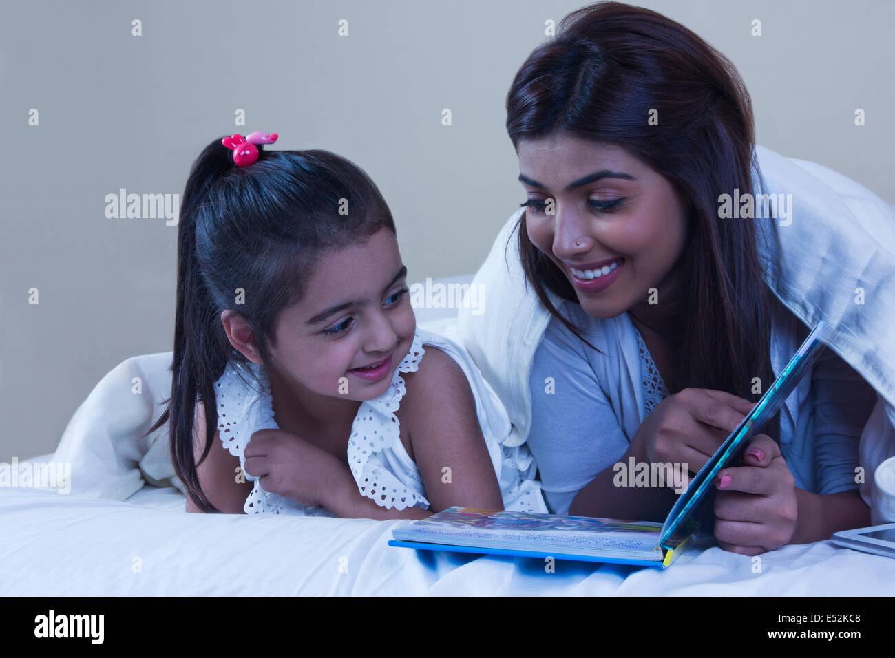 Mutter und Tochter mit Bilderbuch im Bett Stockfoto