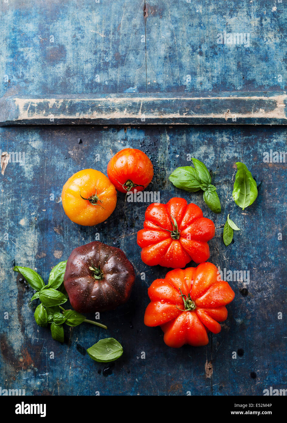 Reife frische bunte Tomaten auf blauem Hintergrund aus Holz Stockfoto