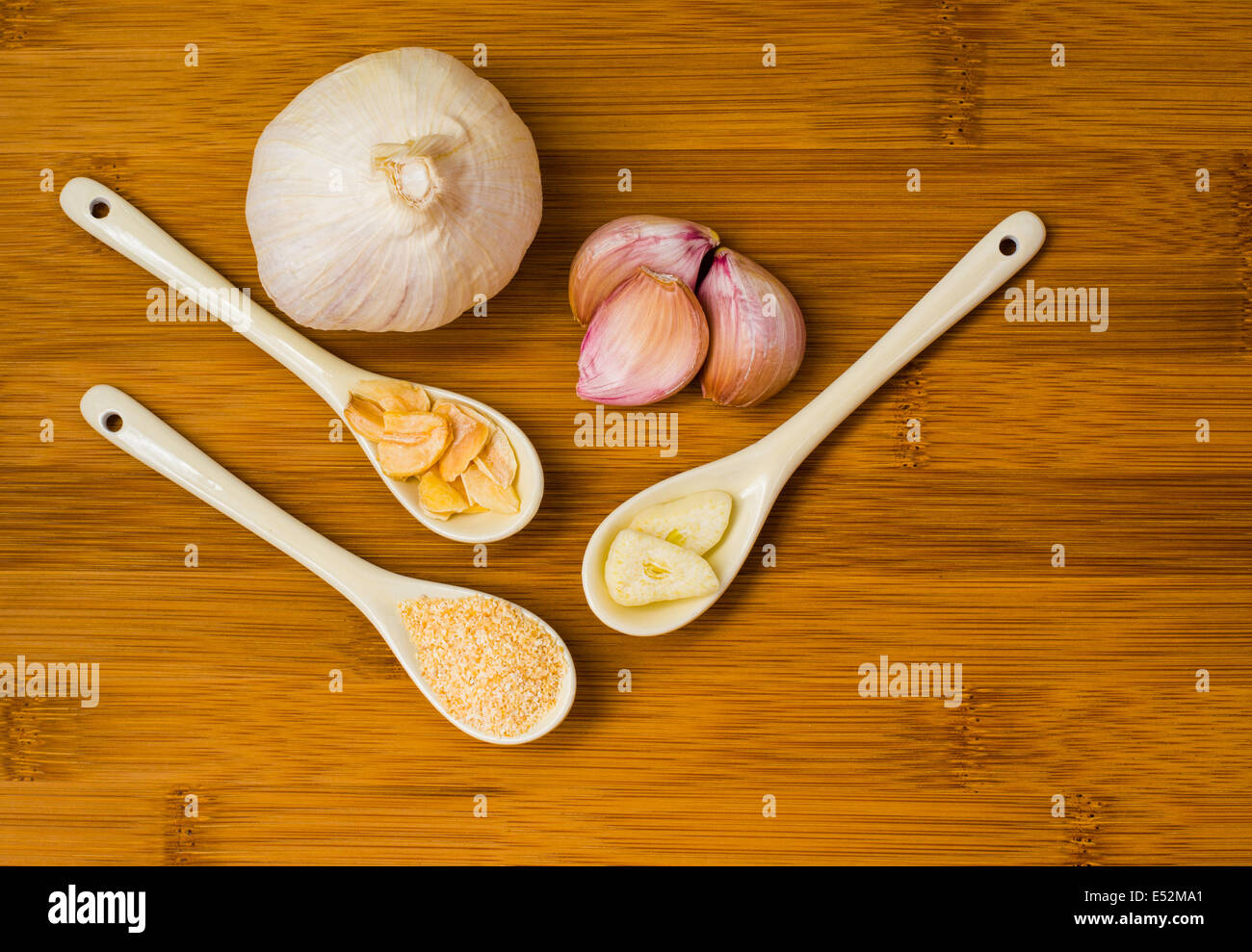 Knoblauchzwiebel mit Knoblauch Flocken, Knoblauch, Salz, Knoblauchzehen und in Scheiben geschnittenen Knoblauch auf einem hölzernen Bambus Schneidebrett Stockfoto