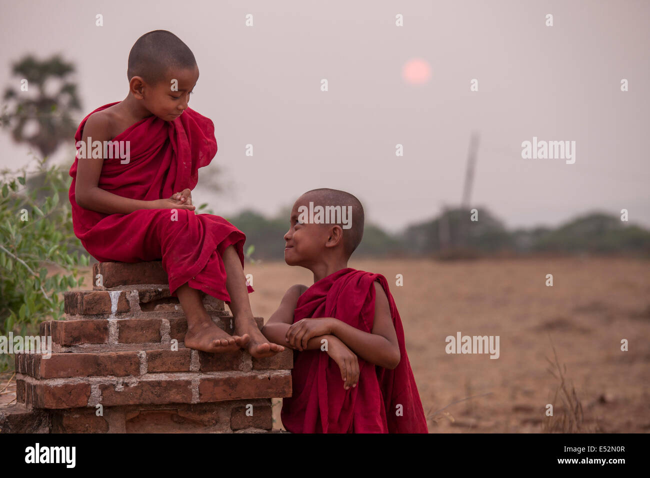 Zwei junge Mönche genießen Sie einen Moment zusammen am Ende des Tages, wenn die Sonne auf der Ebene von Bagan in Myanmar untergeht. Stockfoto