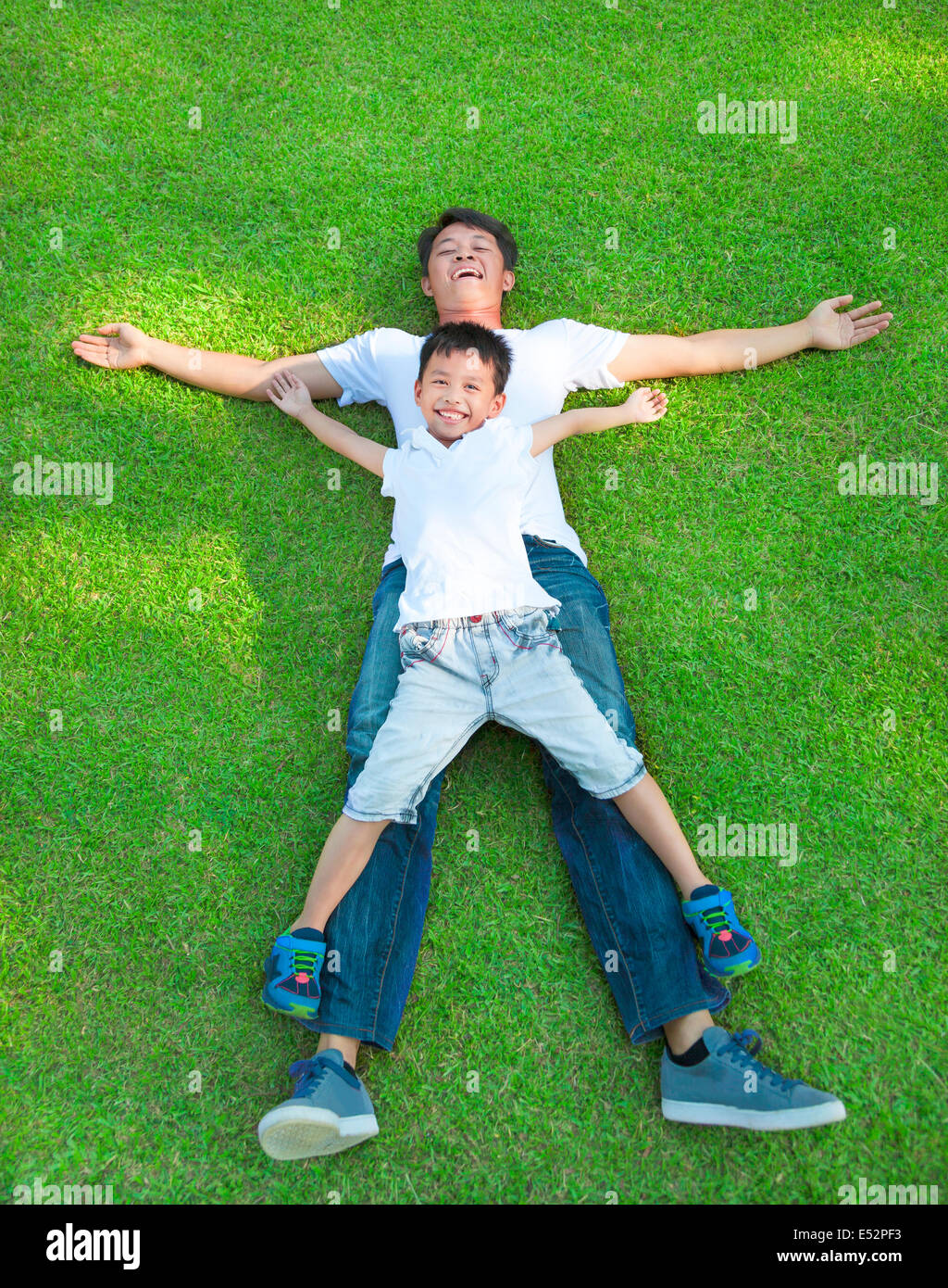 junger Vater und Sohn zusammen auf einer Wiese liegend Stockfoto