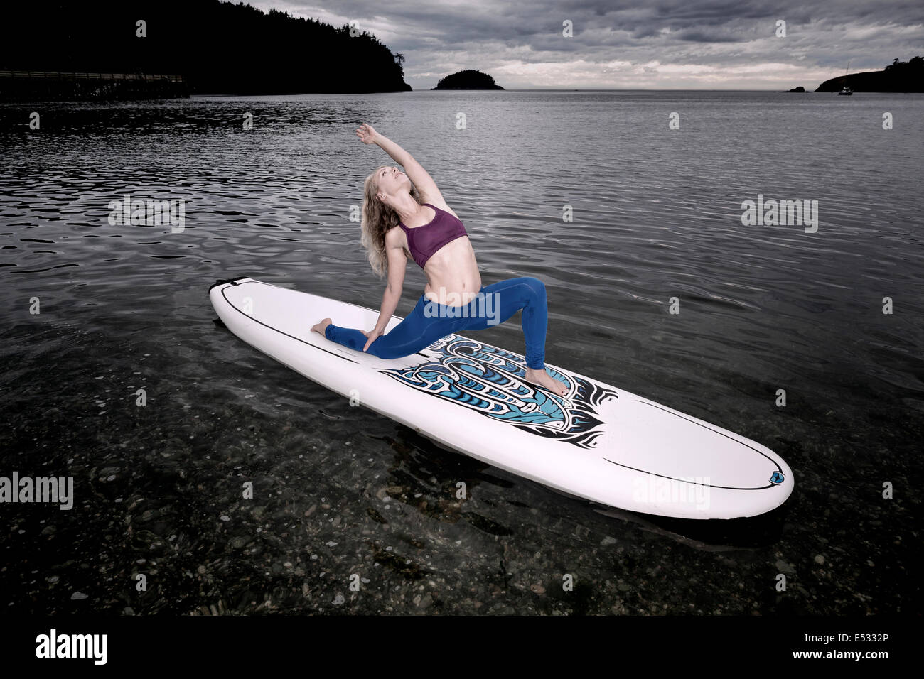 WASHINGTON - Yogalehrerin Carly Hayden Erwärmung bis auf ein SUP (Stand up Paddle Board), in der Bowman-Bucht. Stockfoto