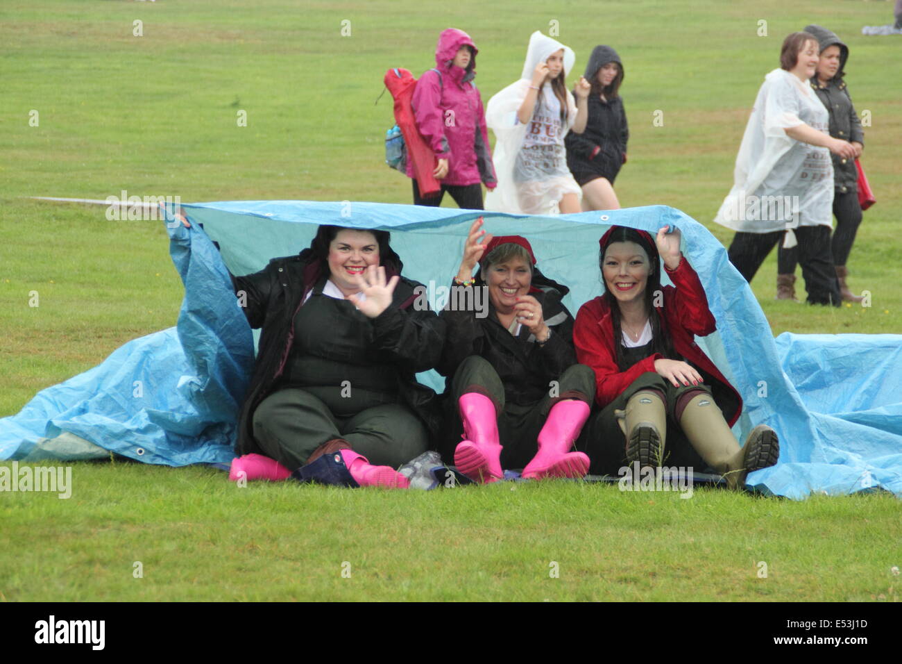 Nottingham East Midlands, UK.  19. Juli 2014. Nach dem Met Office ausgestellt eine Bernstein "bereit sein" Wetter Warnung, Natasha McGeachie (l) aus Nottingham, Rose Hines (c) aus Deutschland und Karen Russell (r) aus Nottingham mutig ein Torrentail Platzregen und brütender Hitze beim jährlichen Pracht Musikfestival in Wollaton Hall in Nottingham. Bildnachweis: Deborah Vernon/Alamy Live-Nachrichten Stockfoto