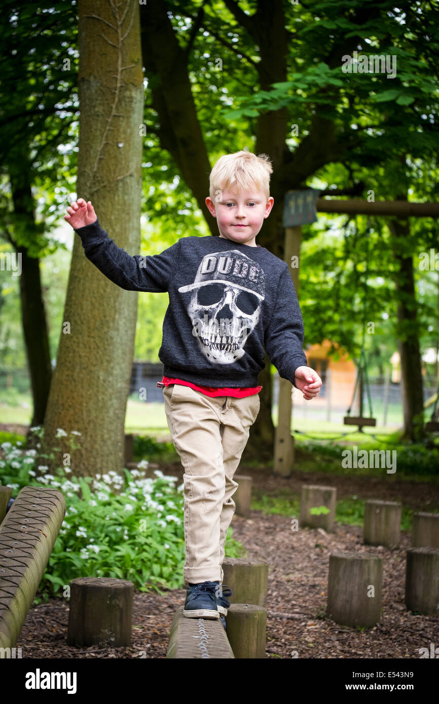 Junge geht selbstbewusst entlang balancieren Trägerende Abenteuerspielplatz Stockfoto