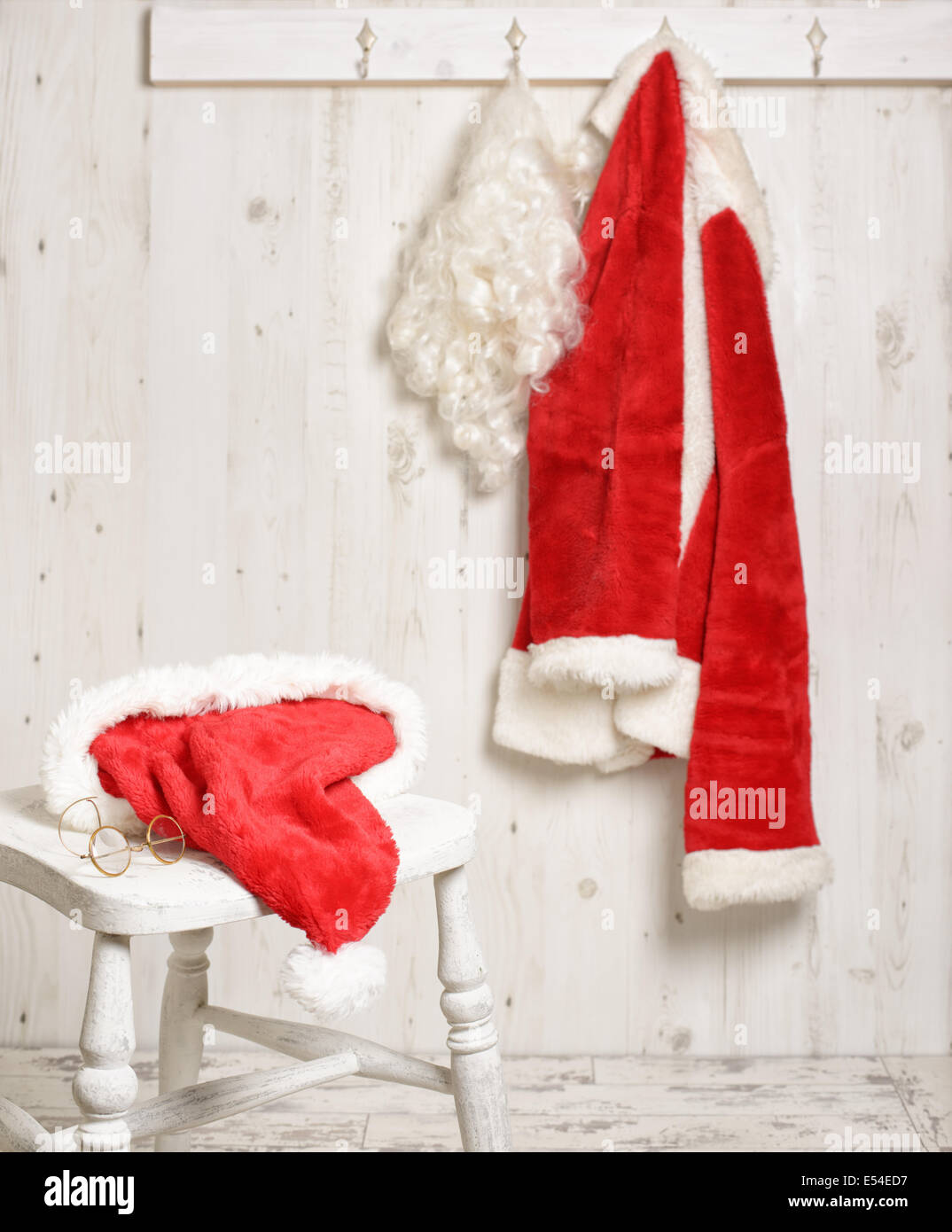 Weihnachtsmann Mütze und Gold umrandeten Angaben auf Hocker mit Mantel hängen im Hintergrund Stockfoto