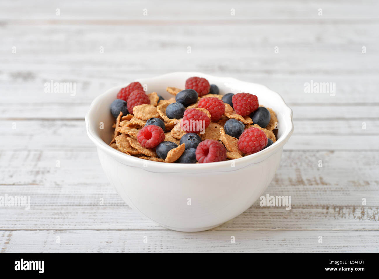 Vollkorn-Flocken in Schüssel mit frischen Beeren auf hellem Hintergrund Stockfoto