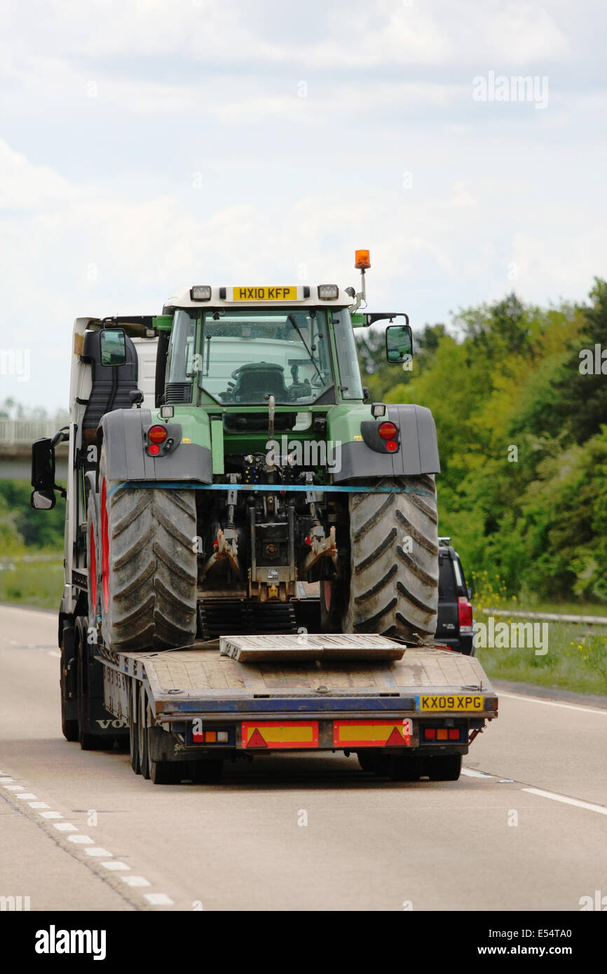 Ein Tieflader schleppen einen Traktor auf der A28 einspurigen Straße in der Nähe von Ashford in Kent, England Stockfoto