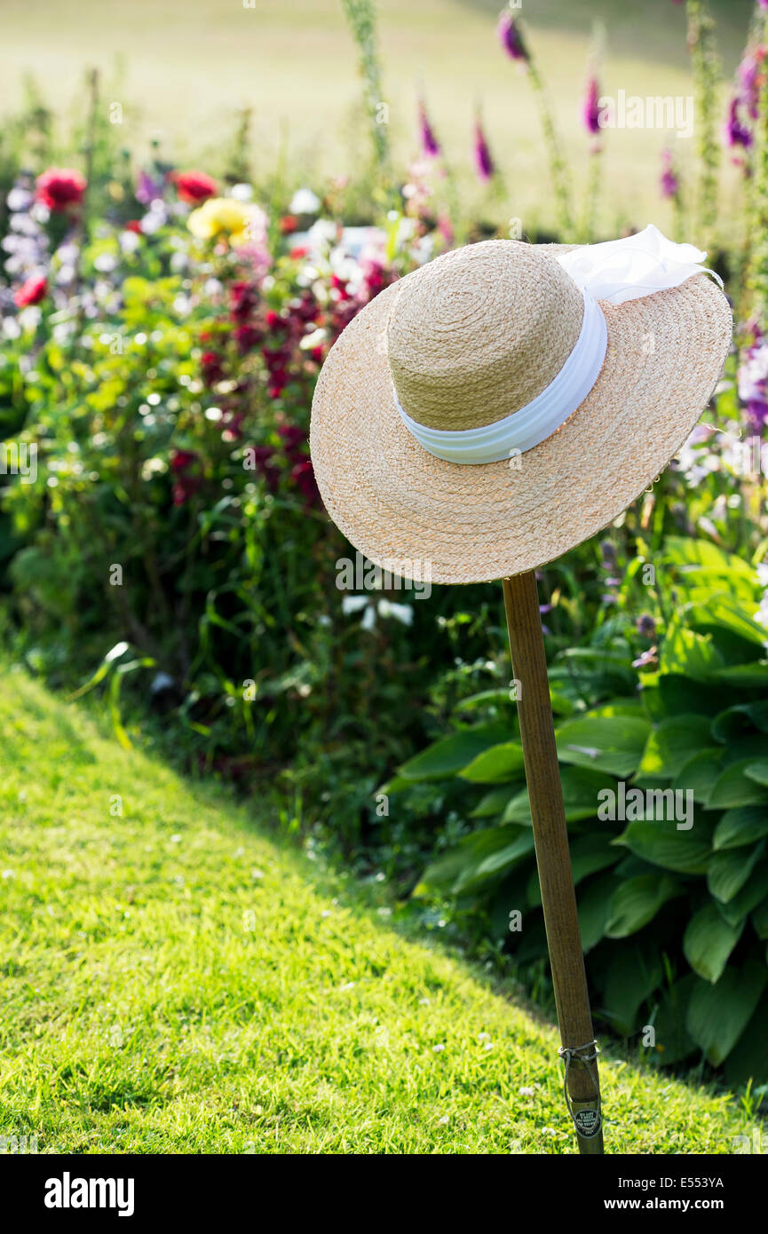 Strohhut auf einem Garten Gabel Griff im Sonnenlicht Stockfoto
